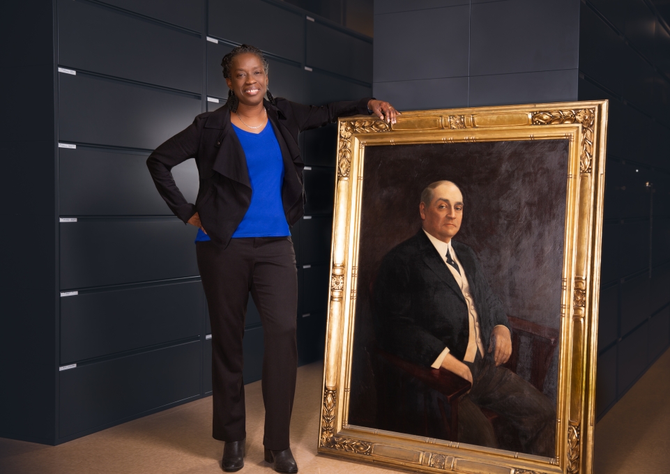Sheila Rayam stands next to life-size portrait of Edward H. Butler Sr.